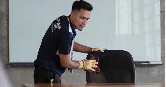 Crew member detailing upholstery in a meeting room