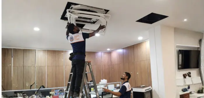 M and E technician servicing ceiling-mounted equipment