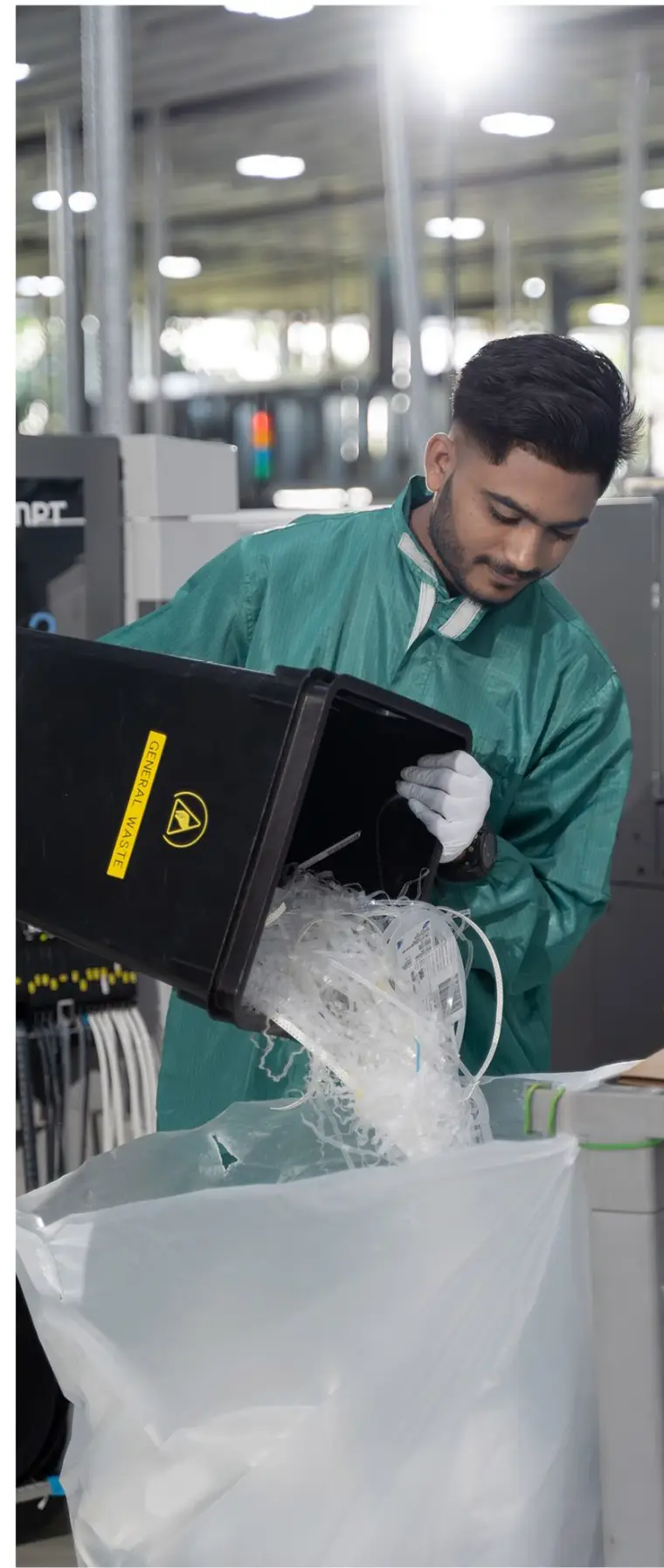 Trained crew member emptying a general waste bin in a production facility